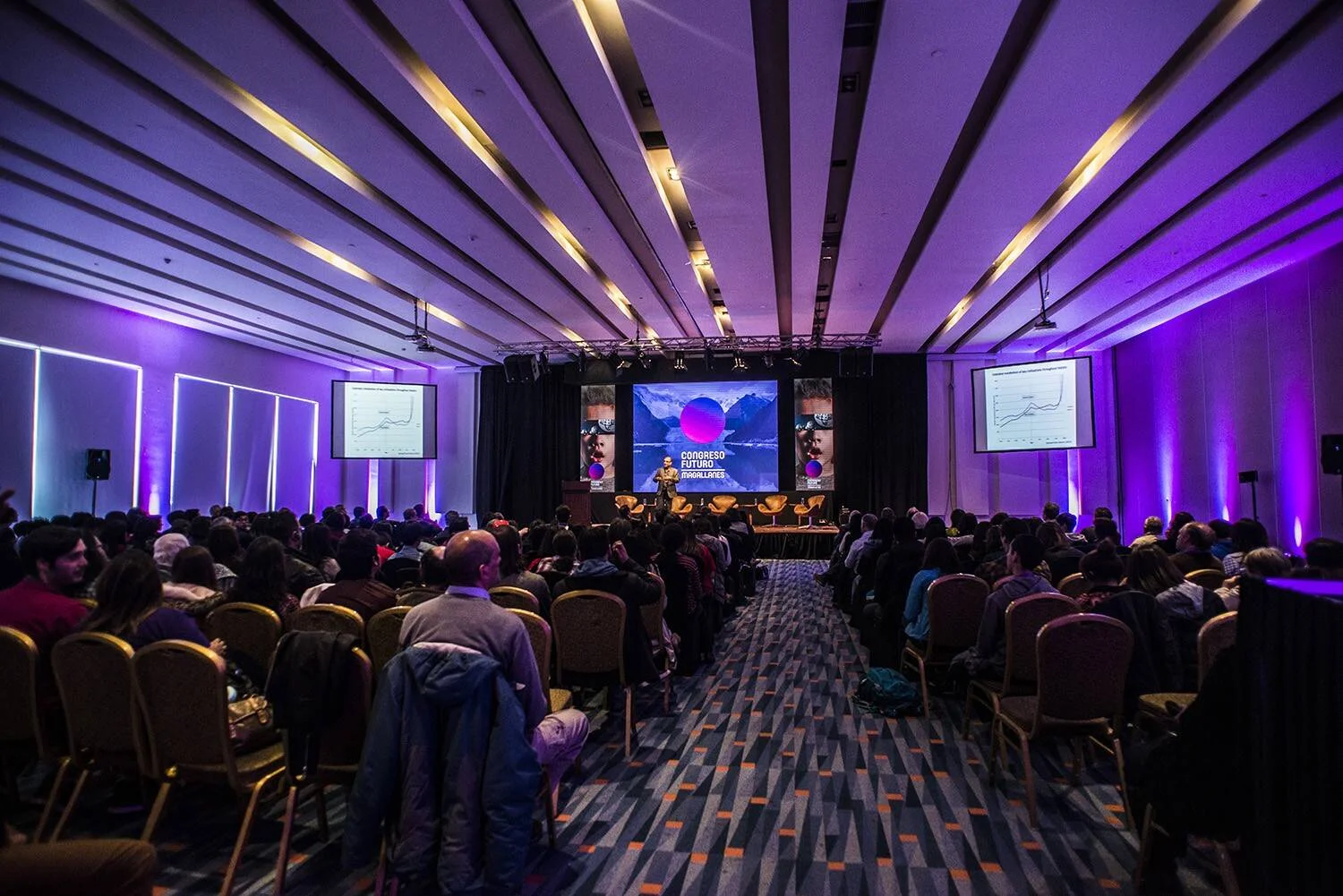 Salón de conferencias con cientos de asistentes durante una sesión plenaria del Congreso Futuro Magallanes, con iluminación púrpura y pantallas en el escenario.