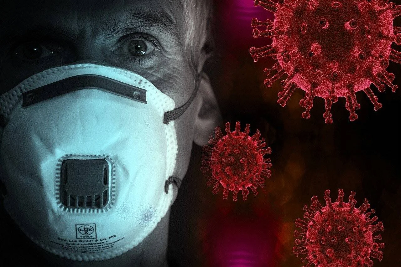 Persona mayor con mascarilla de respiración junto a representaciones digitales en rojo del virus coronavirus sobre fondo oscuro.