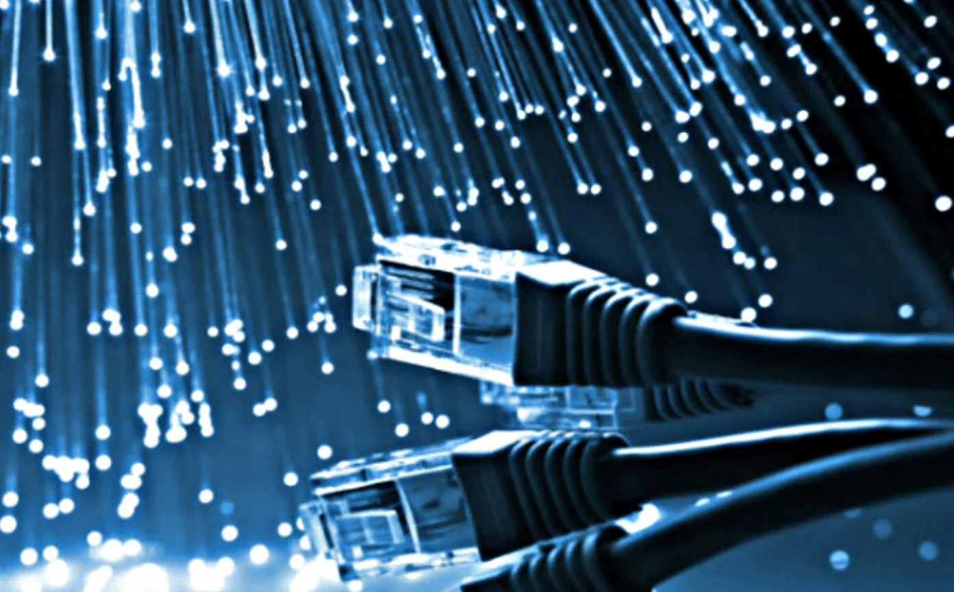 Conectores RJ45 de cables Ethernet frente a un haz de fibras ópticas con luz azul, simbolizando conectividad de internet.