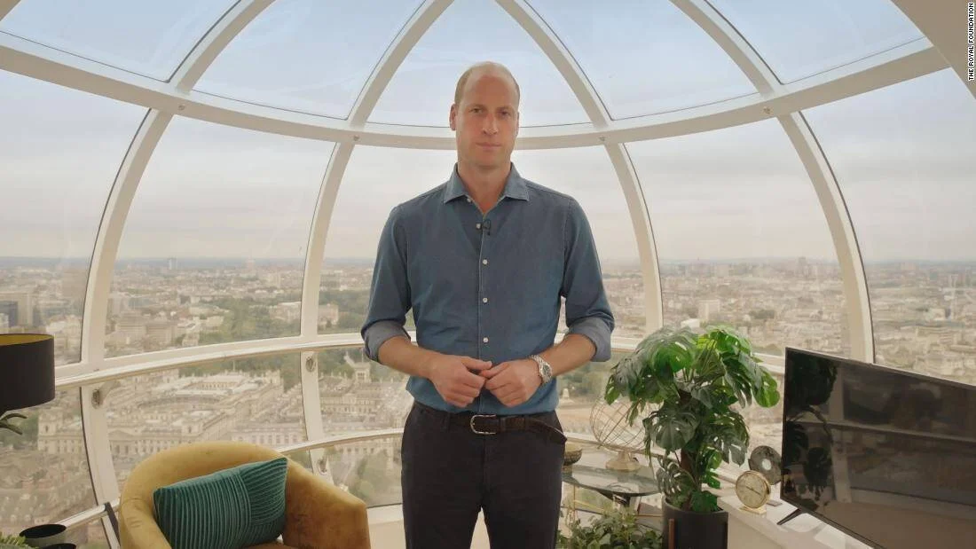 Hombre con camisa azul de pie en una cápsula acristalada con vistas aéreas de Londres al fondo.