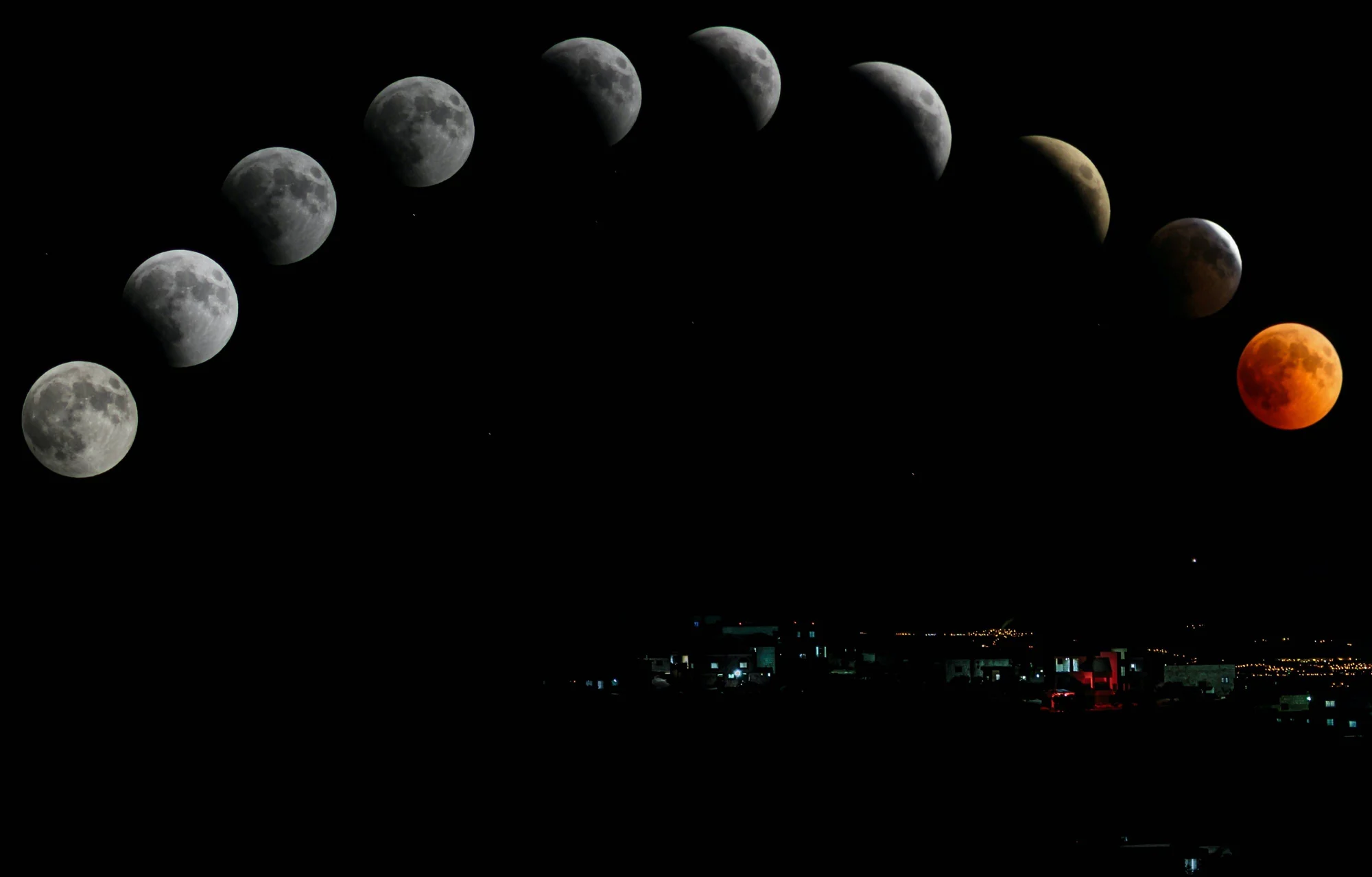 Composición de las fases de un eclipse lunar total, desde luna llena blanca hasta luna de sangre rojiza, sobre una ciudad nocturna.