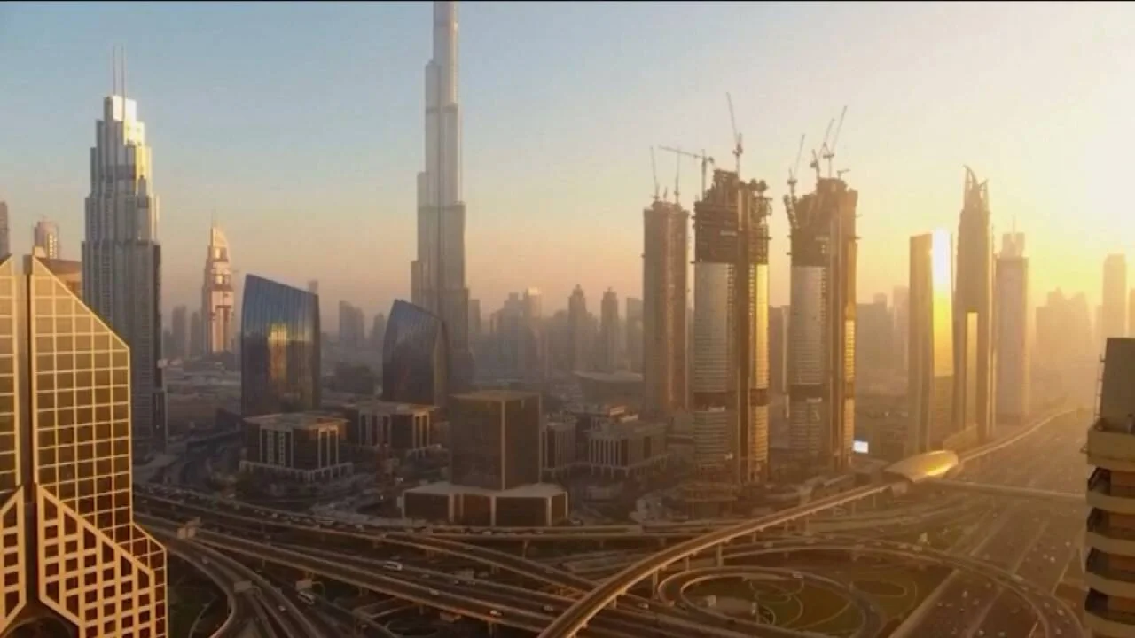 Vista aérea del centro de Dubái al atardecer, con el Burj Khalifa dominando el horizonte y edificios en construcción.