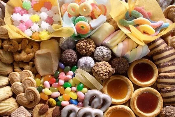Amplio surtido de dulces, gomitas, bombones, galletas y tartaletas de caramelo vistos desde arriba.