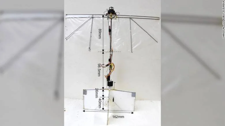 Robot experimental con estructura de alas superiores y plataforma inferior, con cotas de dimensiones en milímetros anotadas sobre la imagen.