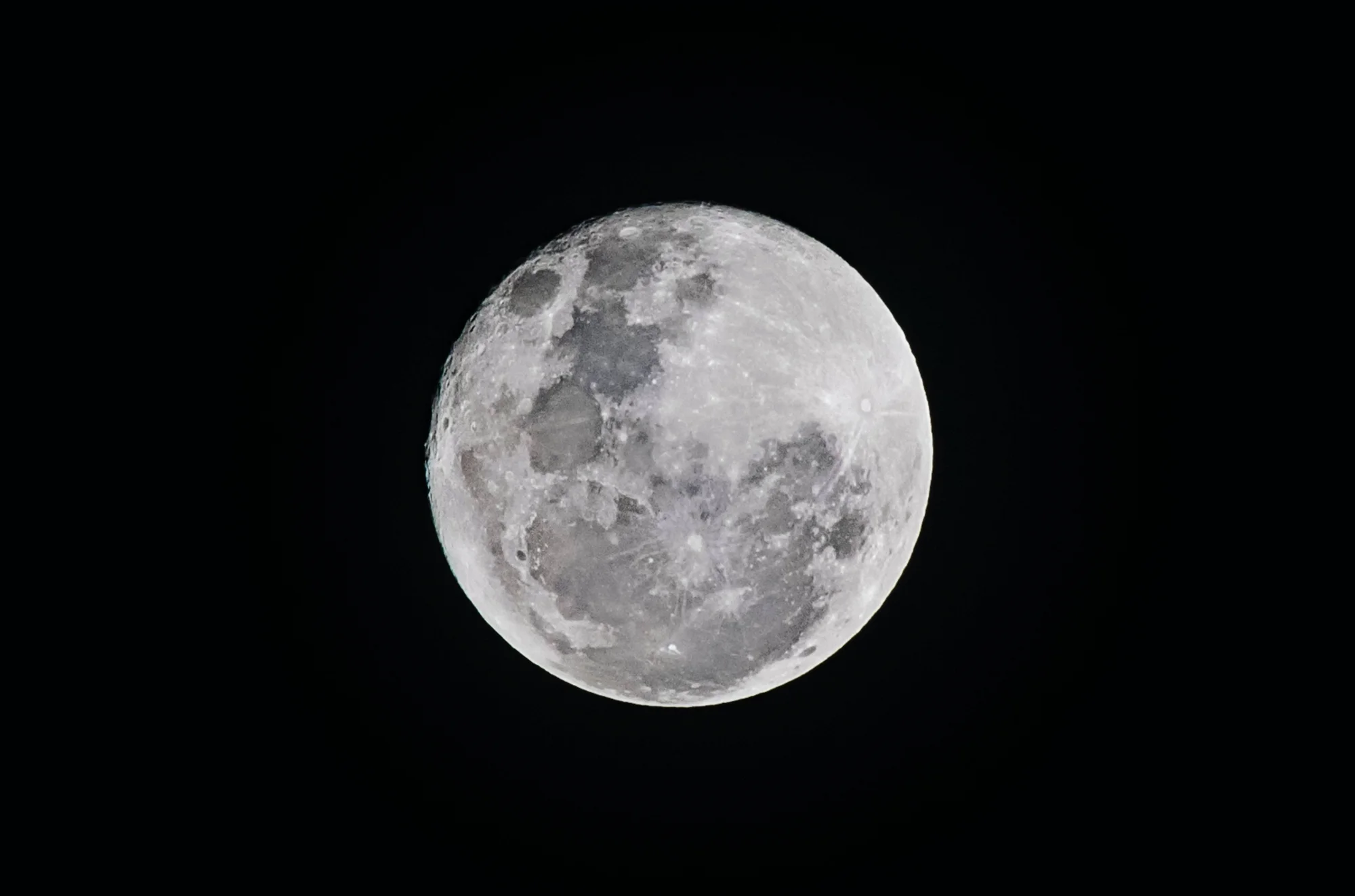 Luna llena fotografiada en detalle contra un cielo completamente oscuro, mostrando sus cráteres y mares lunares.