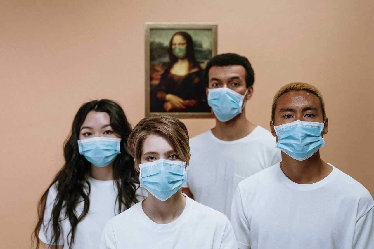 Cuatro jóvenes con mascarillas quirúrgicas frente a una reproducción de la Mona Lisa también con mascarilla, aludiendo a la pandemia.