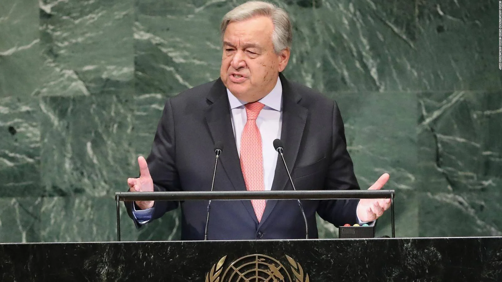 Hombre con traje oscuro y corbata rosa gesticula mientras habla desde el podio oficial de las Naciones Unidas.