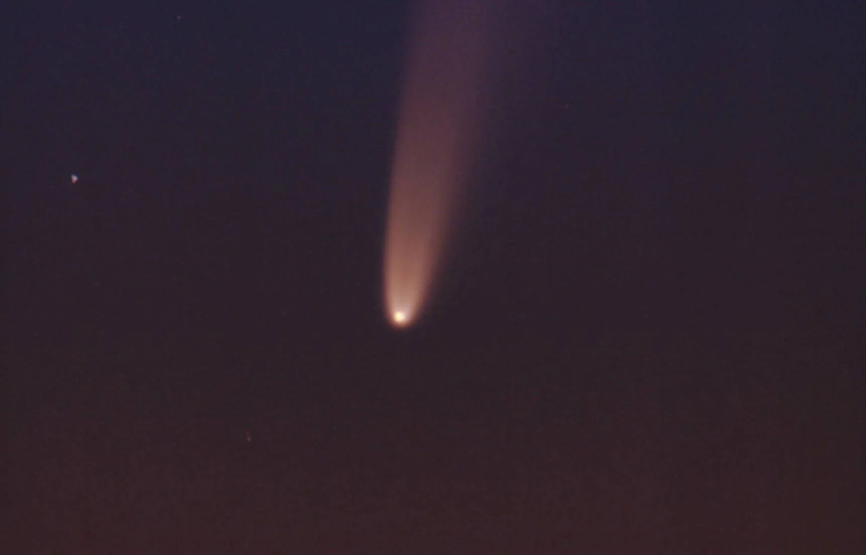 Cometa brillante con una larga cola de polvo visible contra el cielo nocturno oscuro.