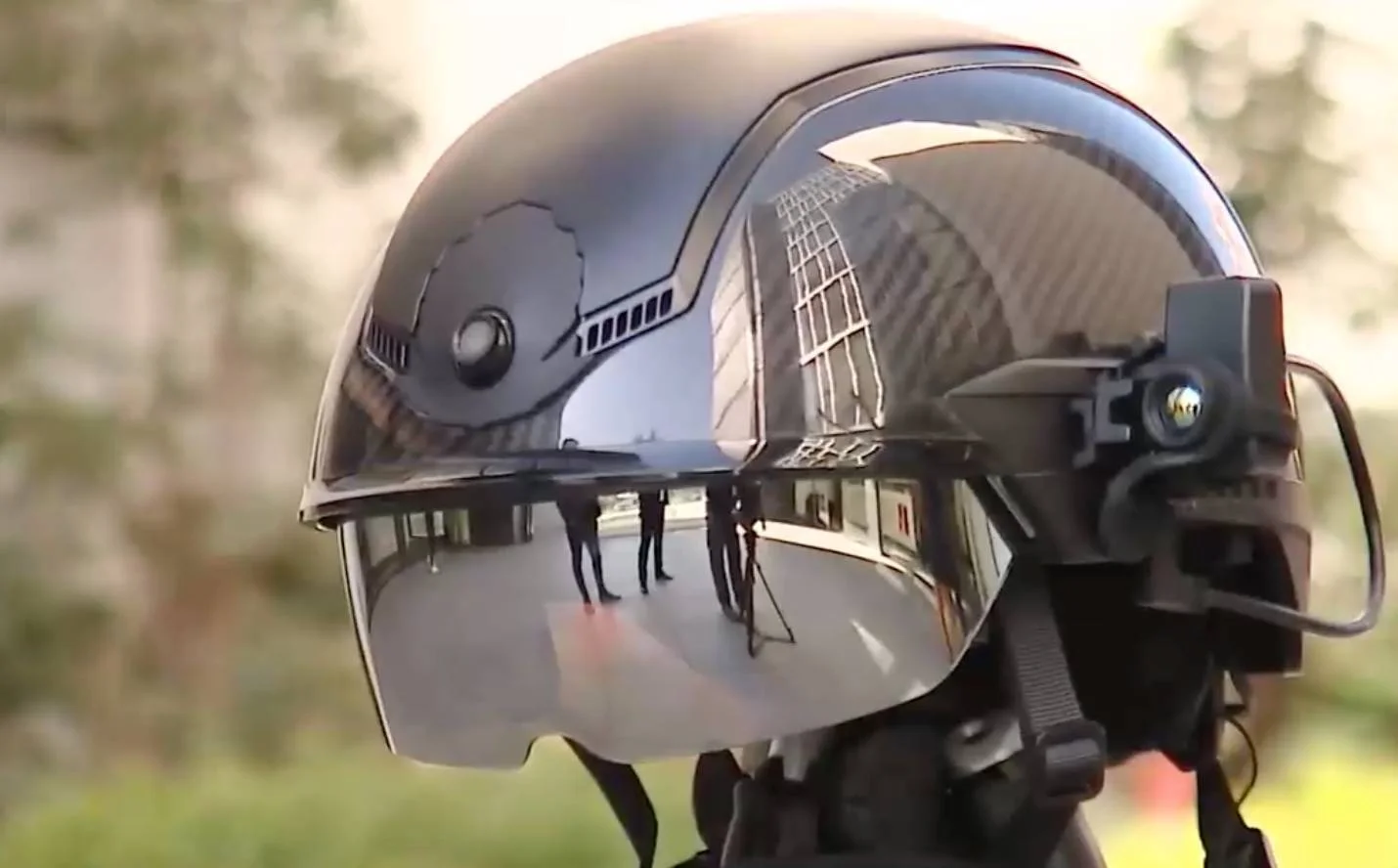 Casco de seguridad de alta tecnología con visor reflectante y dispositivo lateral tipo cámara o pantalla integrada.