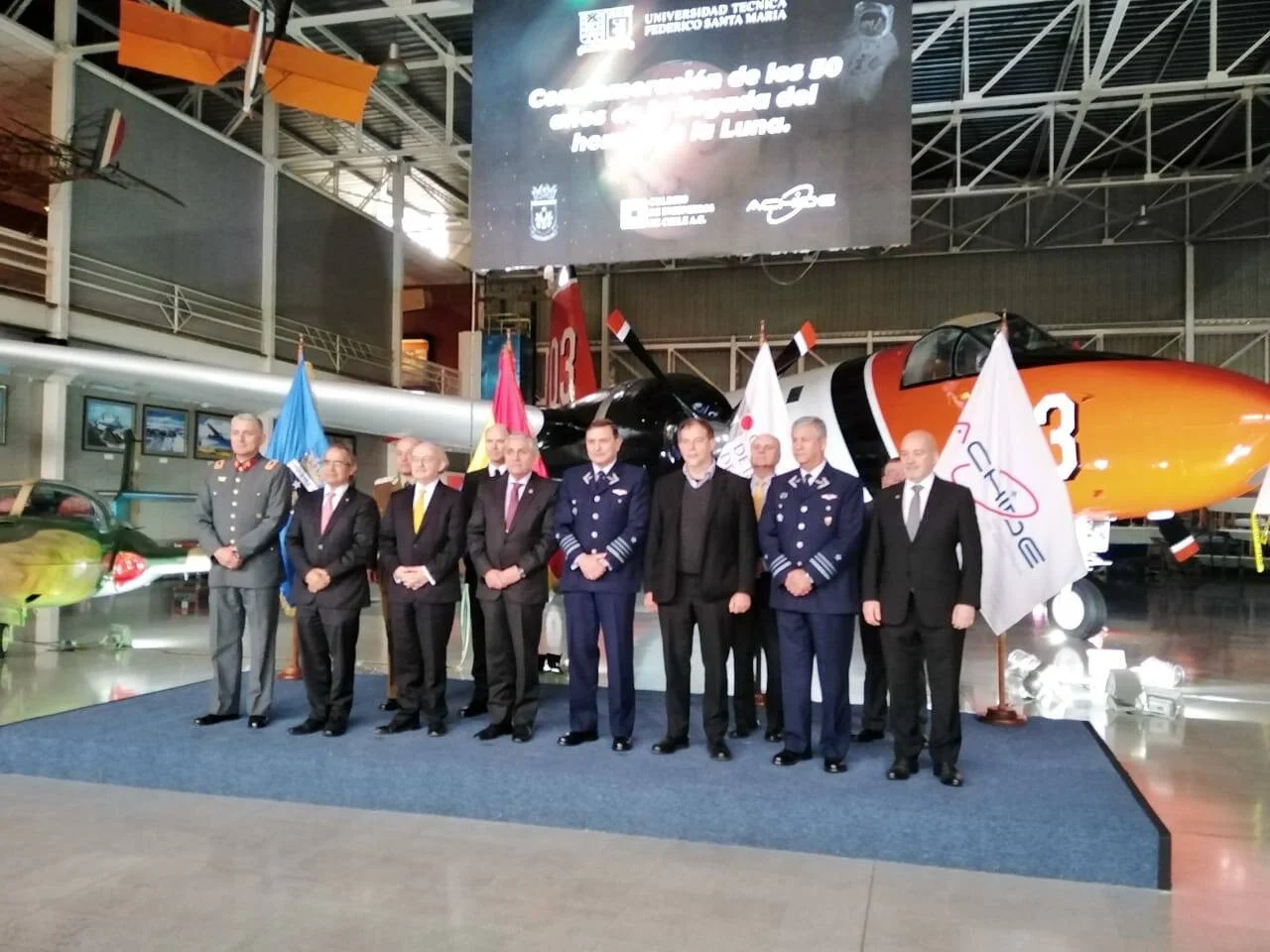 Grupo de autoridades civiles y militares posando en hangar durante conmemoración de los 50 años de la llegada del hombre a la Luna, organizada por la Universidad Técnica Federico Santa María.