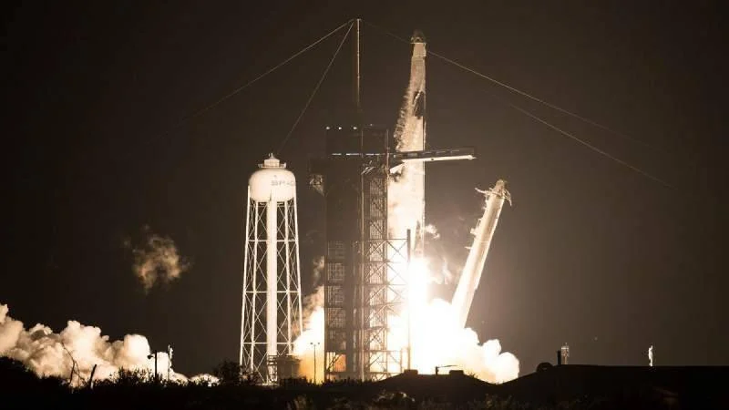Cohete Falcon 9 de SpaceX despegando de noche desde la plataforma de lanzamiento, rodeado de llamas y nubes de vapor.