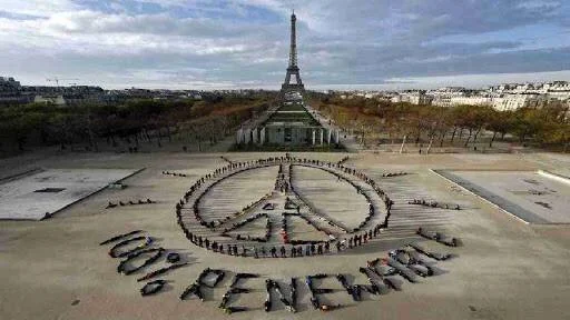 Activistas forman un símbolo de la paz con la leyenda '100% Renewable' frente a la Torre Eiffel en París.