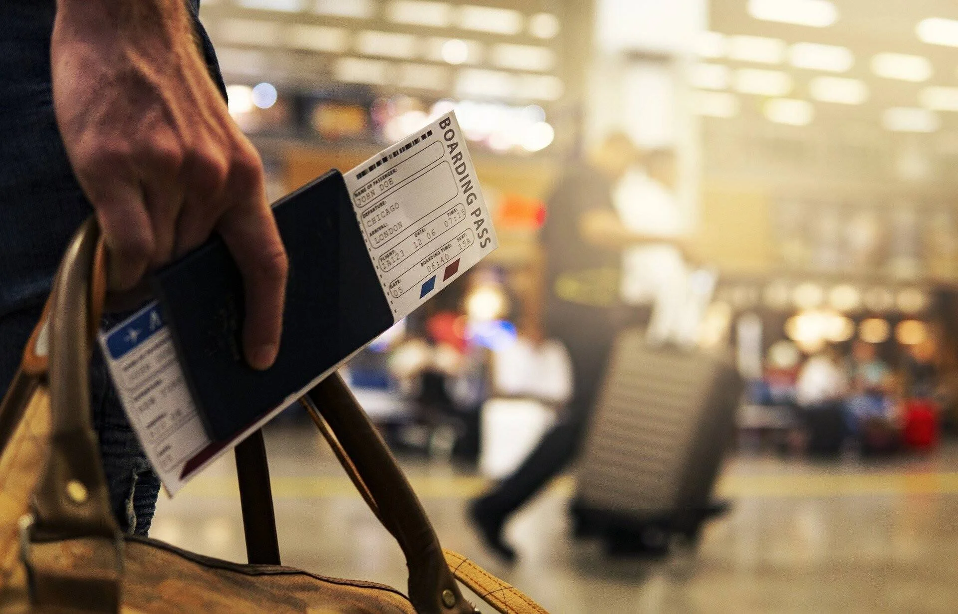 Mano sosteniendo un pasaporte con una tarjeta de embarque en la sala de espera de un aeropuerto.