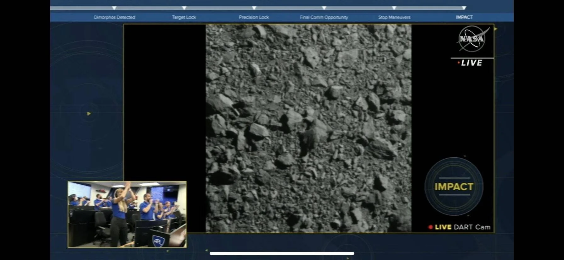 Transmisión en vivo de la NASA mostrando la superficie rocosa del asteroide Dimorphos capturada por la sonda DART momentos antes del impacto, con el equipo celebrando al fondo.