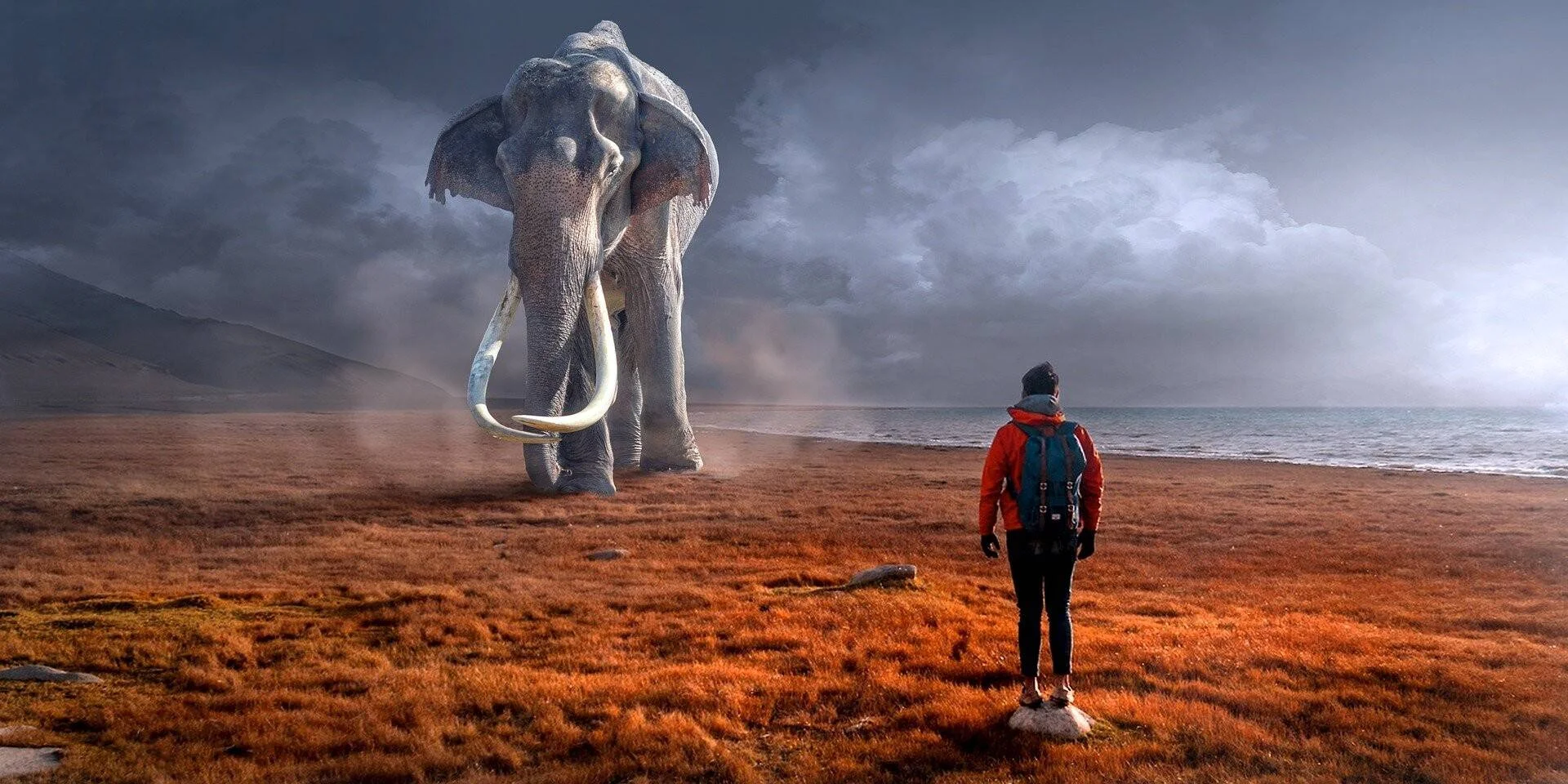 Ilustración digital de una persona con mochila observando un enorme mamut con colmillos en una llanura rojiza junto al mar.