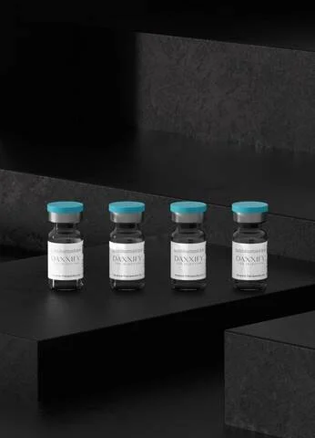 Cuatro frascos del producto Daxxify con tapas azules alineados sobre una plataforma oscura de fondo negro.