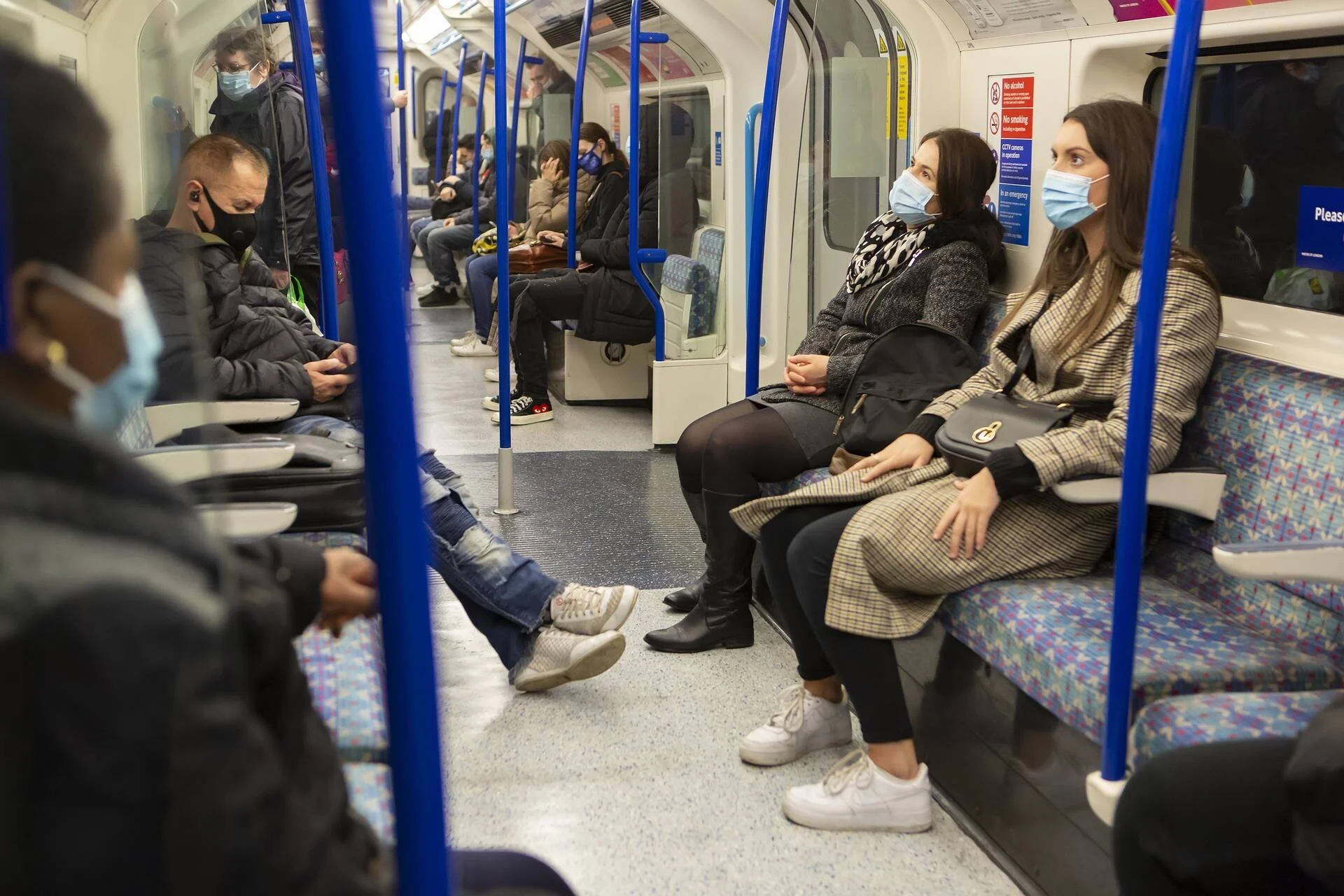 Varios pasajeros con mascarillas sanitarias viajan sentados en el interior de un vagón de metro.