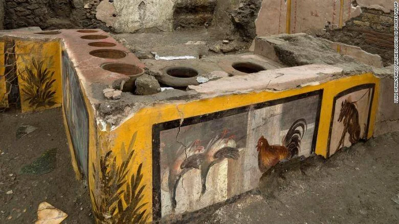 Mostrador de un termopolio romano excavado en Pompeya, decorado con frescos de animales y con recipientes incrustados para conservar alimentos.