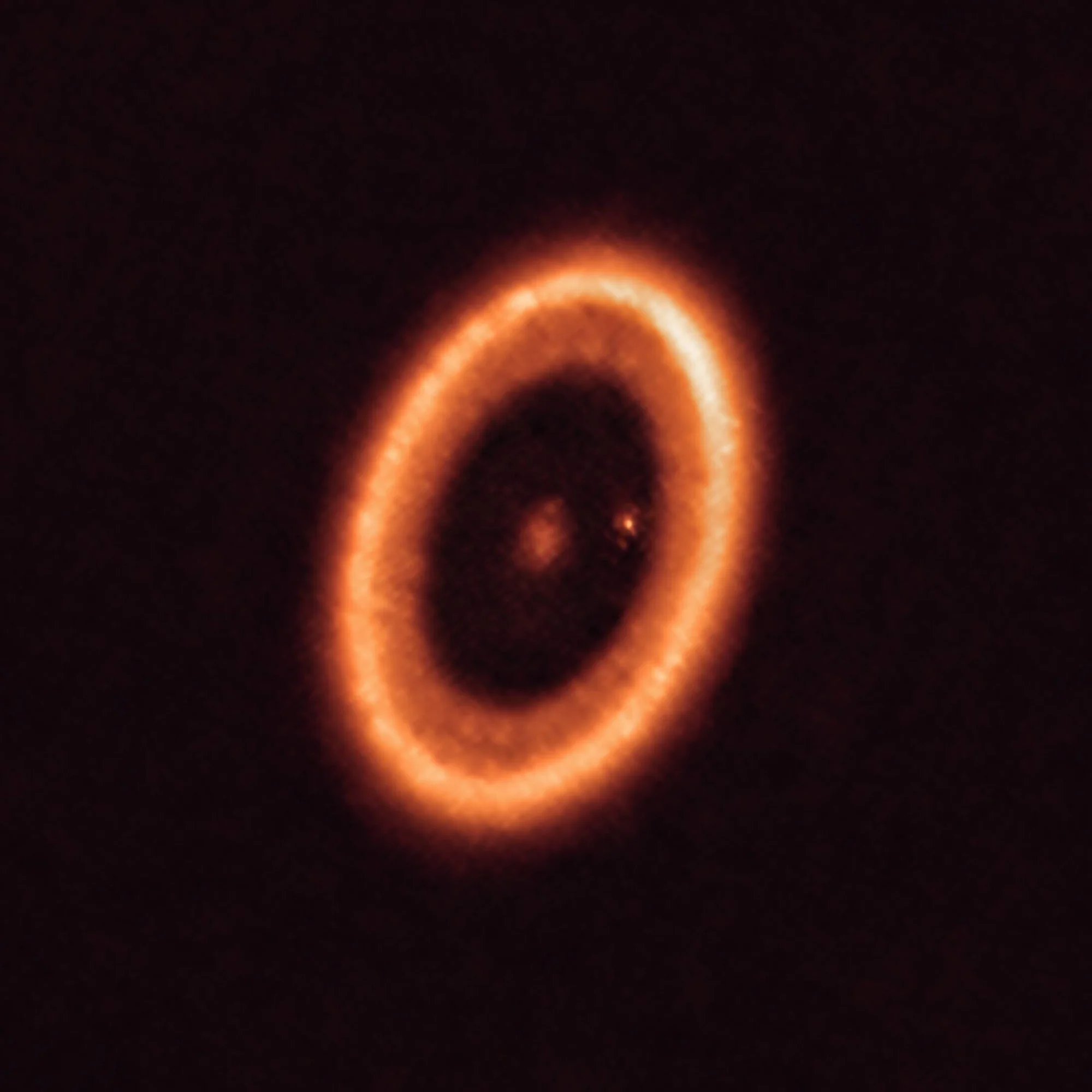 Imagen astronómica de un disco protoplanetario con un anillo luminoso naranja rodeando una estrella central, captada por radiotelescopio.