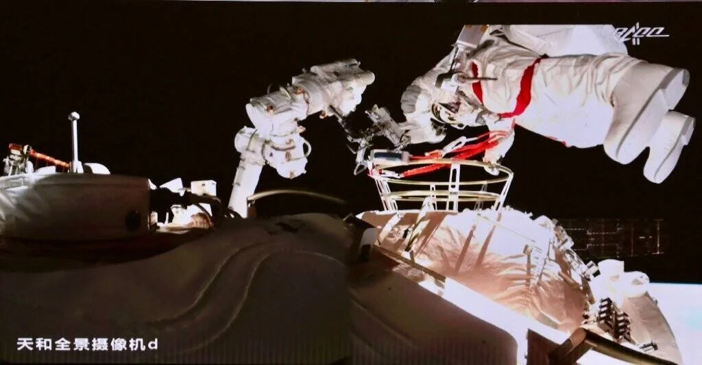 Taikonautas con trajes espaciales realizan una caminata extravehicular en el exterior de la estación espacial china Tiangong.