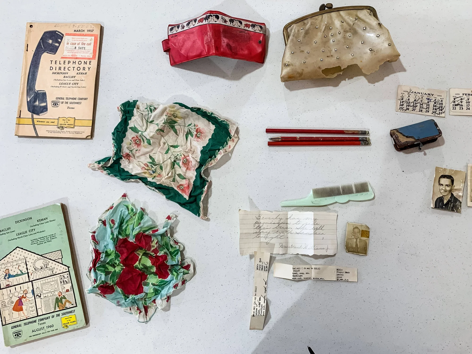 Colección de objetos personales de mediados del siglo XX: directorios telefónicos de 1957 y 1960, pañuelos florales, monedero, peineta, lápices, fotos y notas manuscritas.