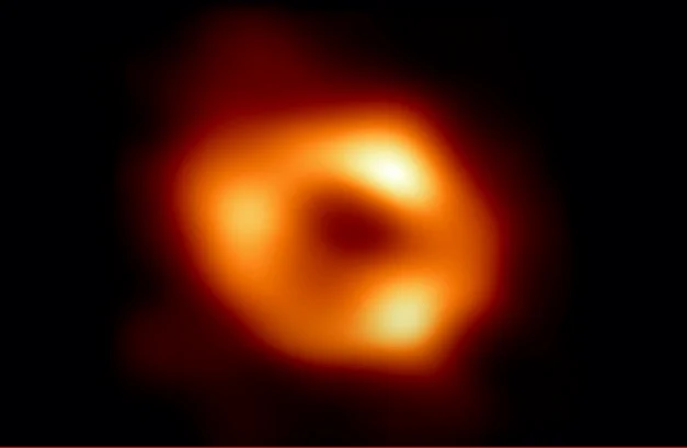 Anillo luminoso anaranjado que rodea la sombra central del agujero negro supermasivo Sagitario A*, en el centro de la Vía Láctea.