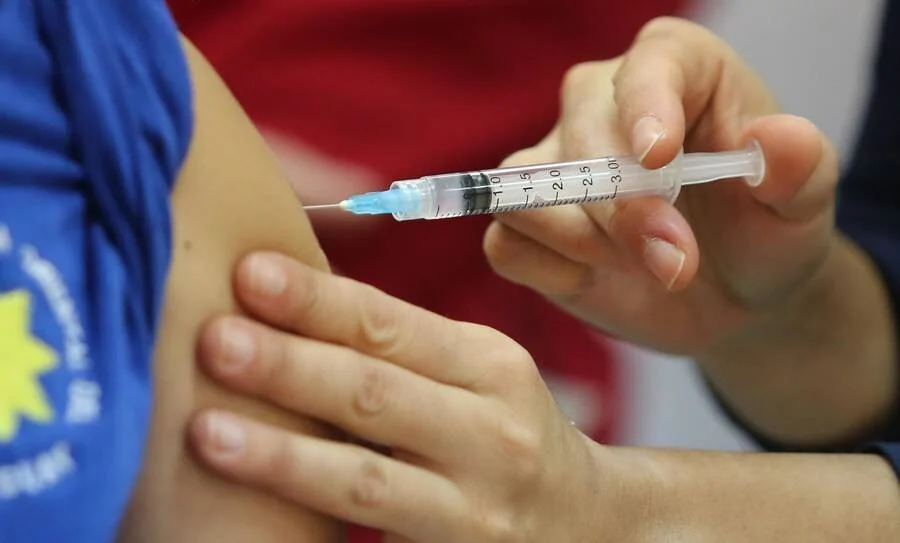 Profesional de salud aplica una inyección con jeringa en el brazo de una persona.