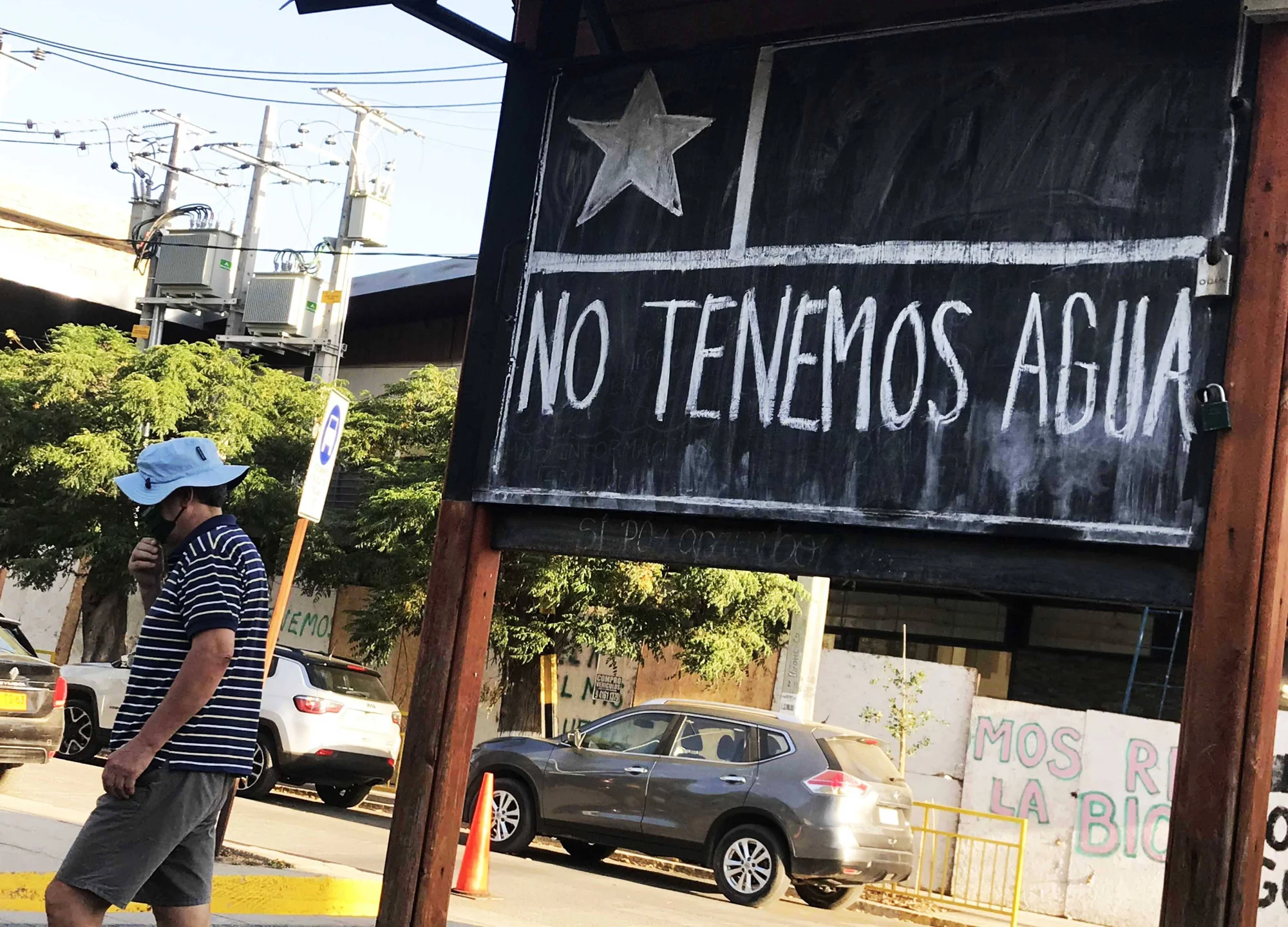Un peatón camina junto a un cartel con la bandera de Chile que dice 'No Tenemos Agua', en protesta por la escasez hídrica.