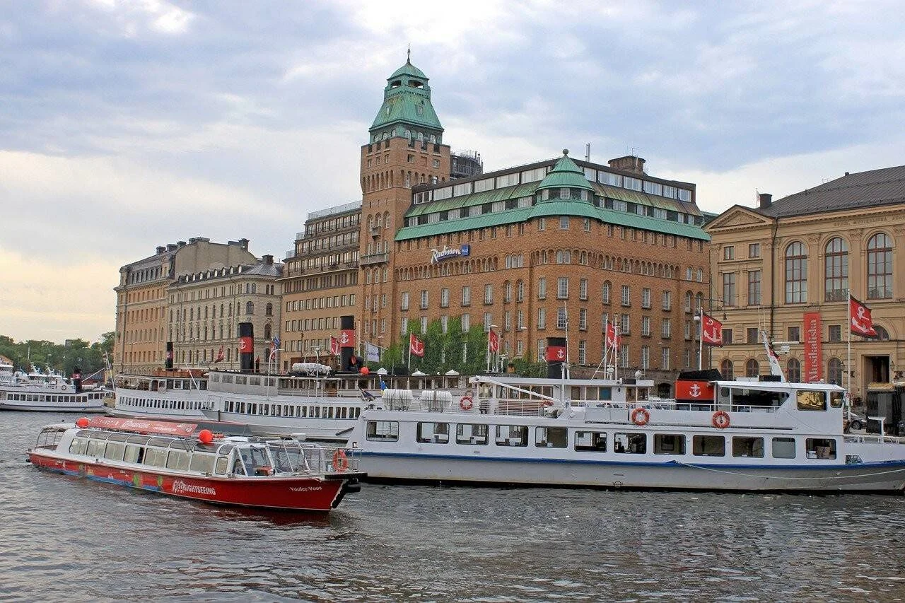 Embarcaciones turísticas amarradas en el canal frente al hotel Radisson y edificios históricos de Estocolmo.