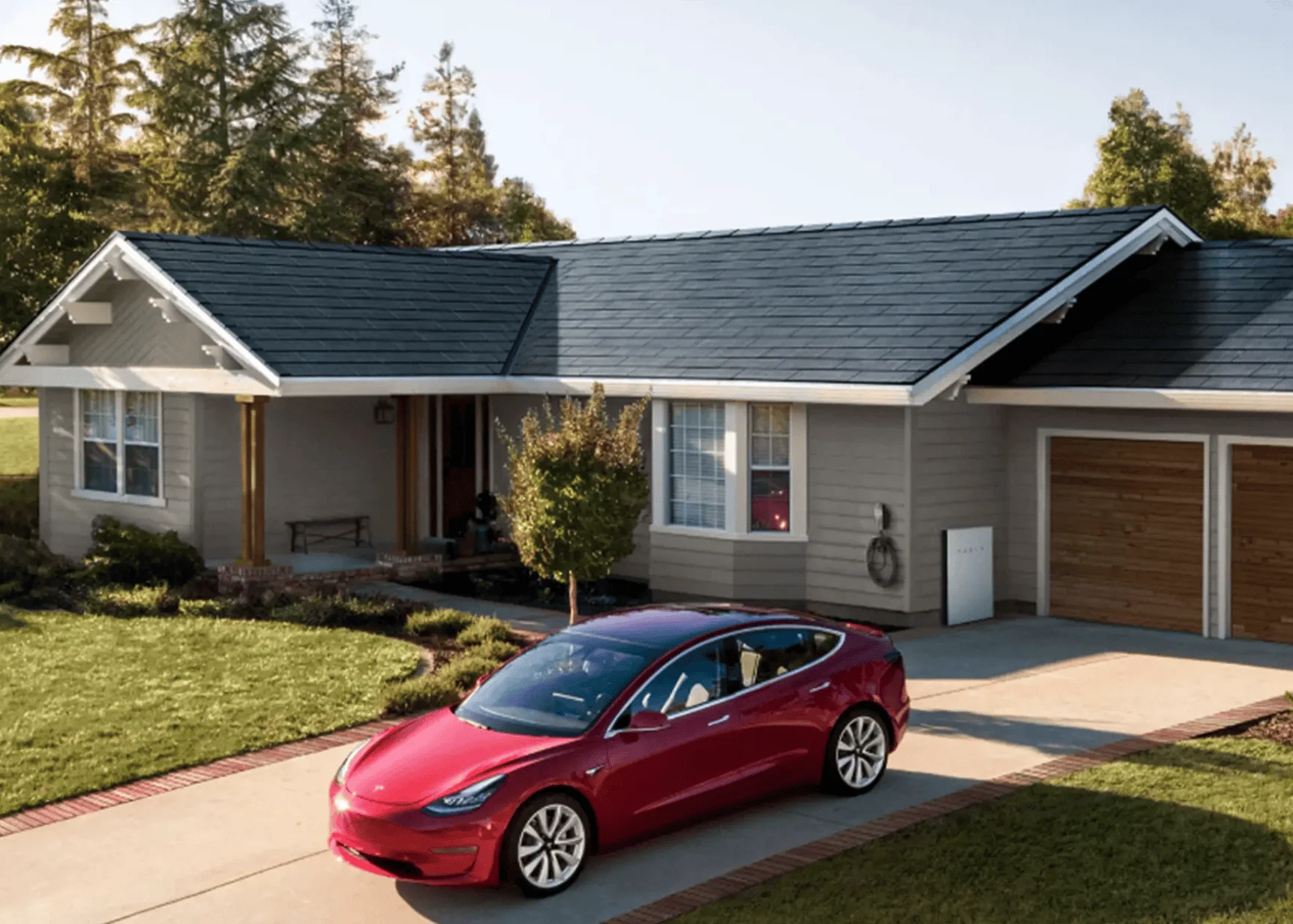Auto eléctrico Tesla rojo estacionado frente a una casa con techo solar integrado y batería doméstica Powerwall.