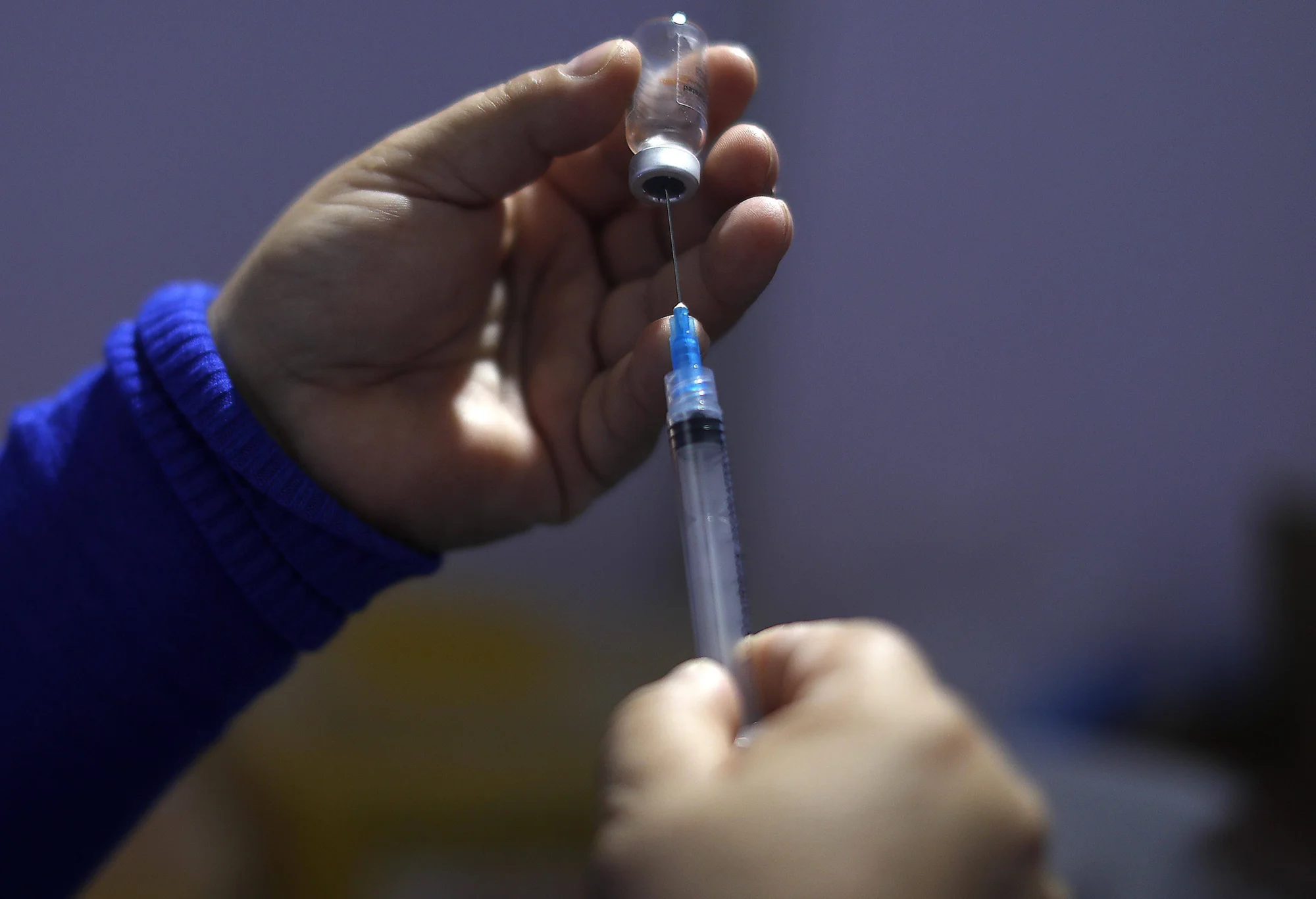 Profesional de salud extrae dosis de vacuna de un frasco con una jeringa.