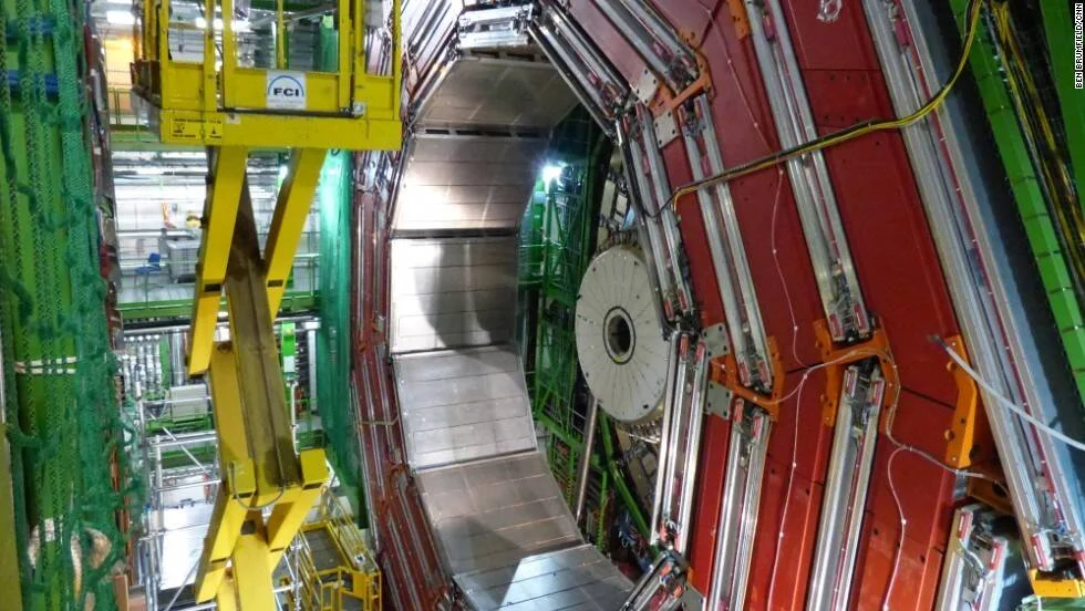 Vista interior del túnel del Gran Colisionador de Hadrones con enormes imanes superconductores rojos y estructura metálica cilíndrica.