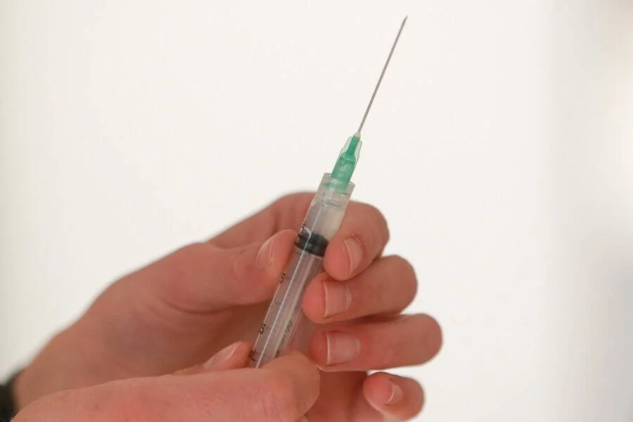 Una mano sostiene una jeringa médica con aguja lista para su uso.