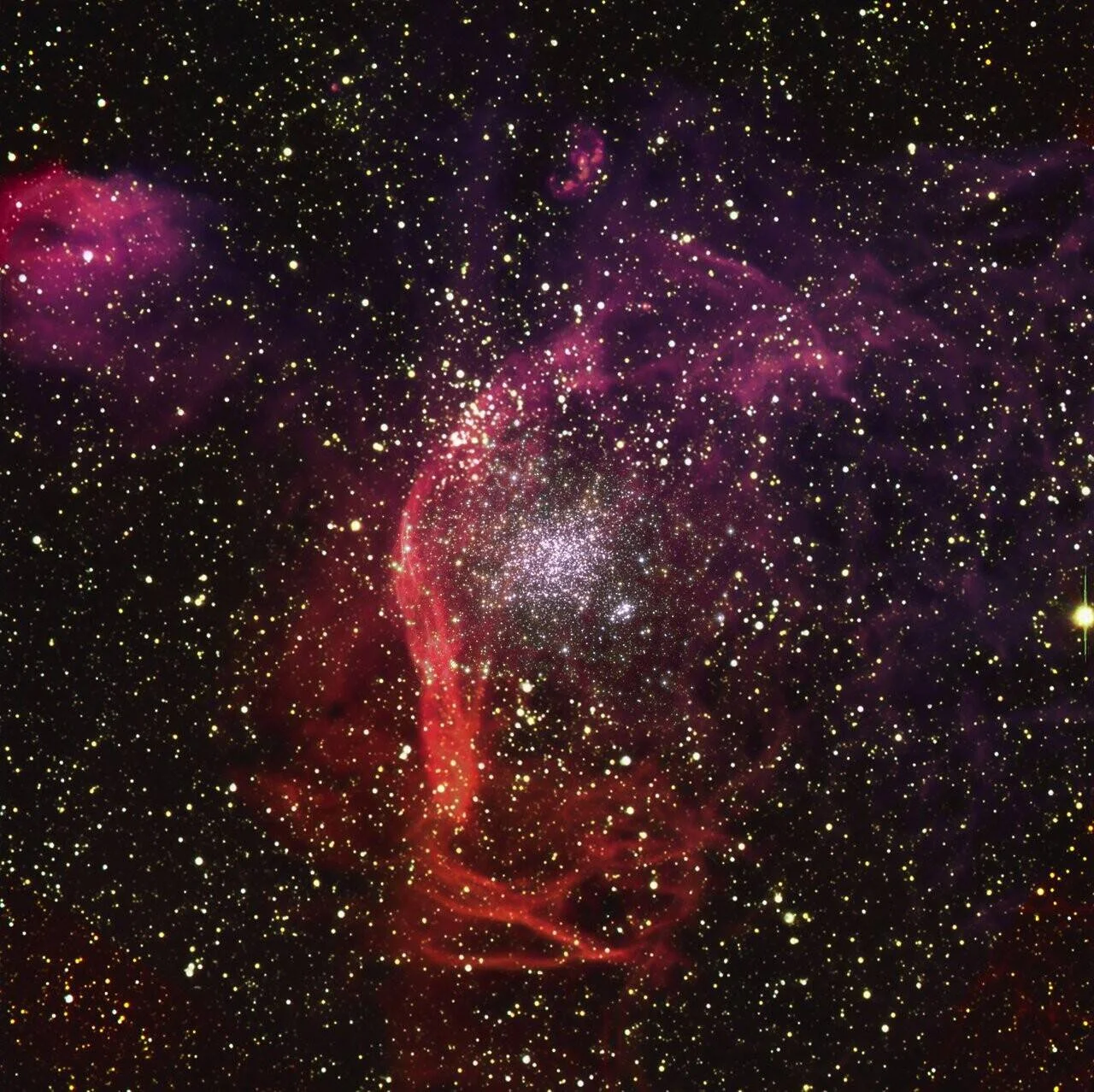 Cúmulo globular de estrellas rodeado por filamentos de gas rojo y nubes de nebulosa púrpura en el espacio profundo.