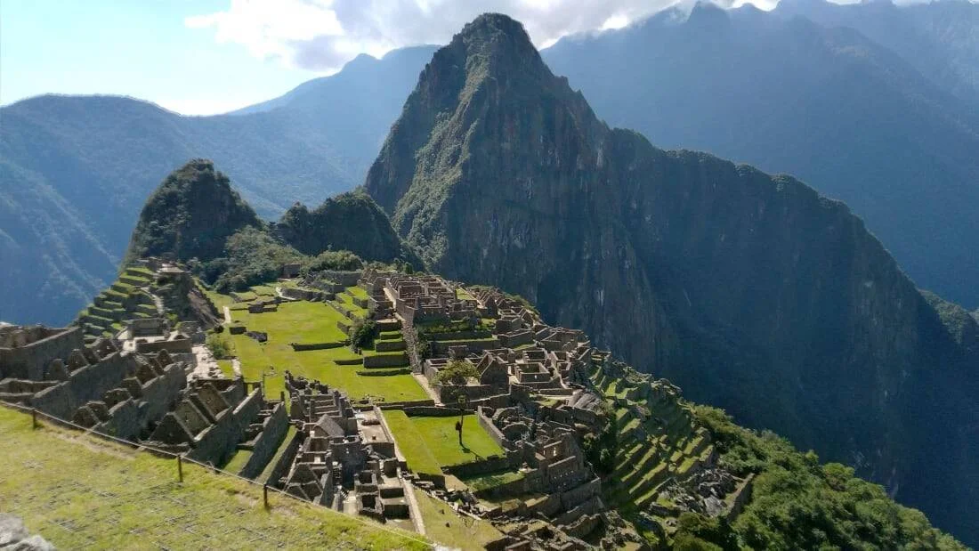 Vista panorámica de las ruinas incas de Machu Picchu con terrazas verdes y el pico Huayna Picchu al fondo.