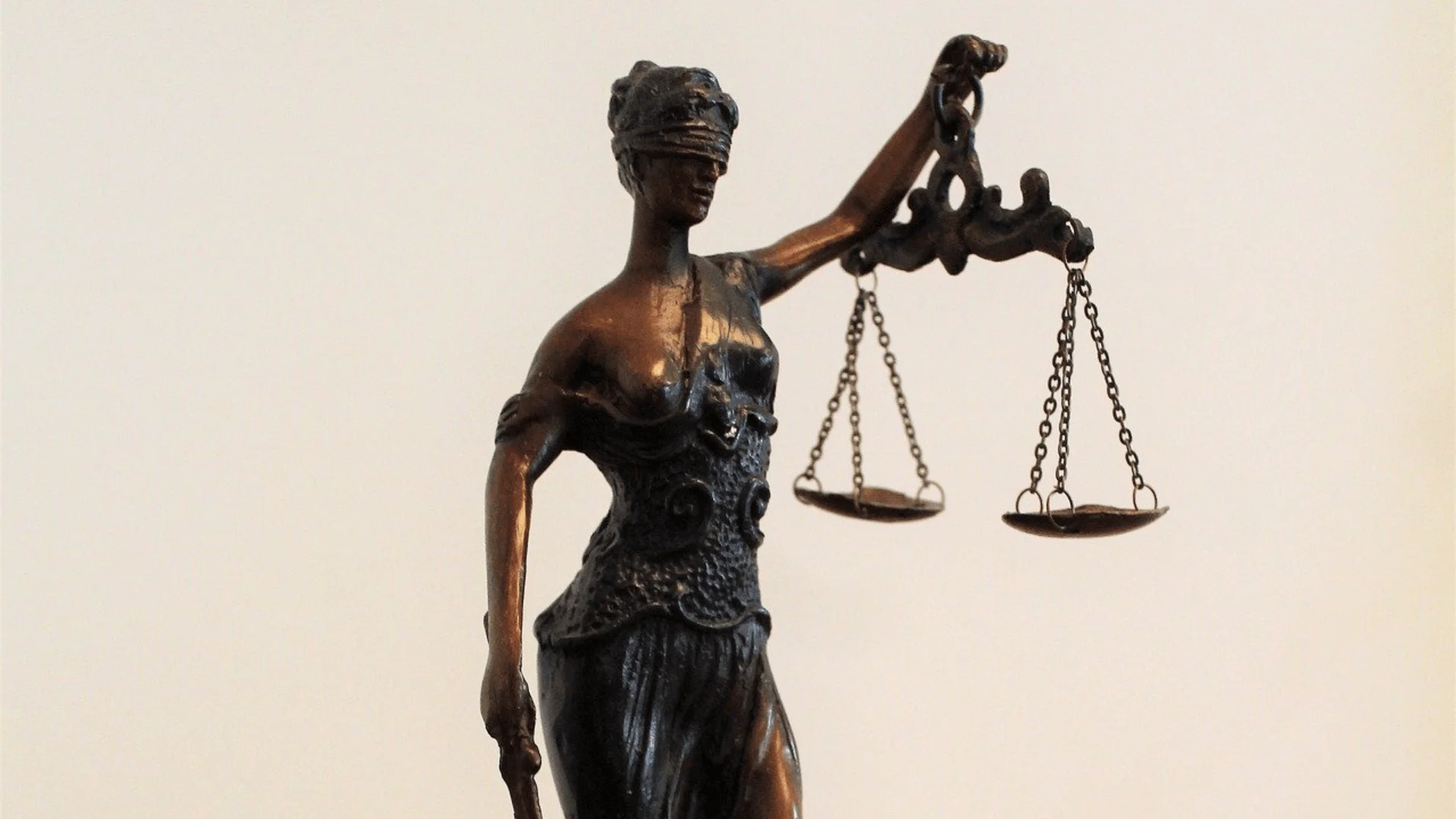 Figura de bronce de la diosa Temis con los ojos vendados, sosteniendo una balanza, símbolo de la justicia imparcial.
