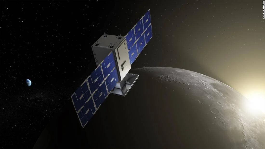 Representación artística de un pequeño satélite con paneles solares azules orbitando la Luna, con la Tierra visible al fondo.