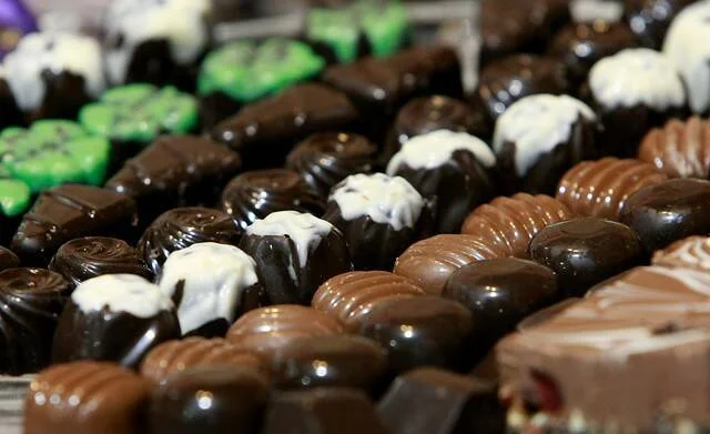 Bandeja con bombones de chocolate oscuro y con leche, algunos decorados con chocolate blanco y otros de colores.