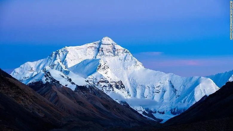 Imponente montaña cubierta de nieve iluminada con luz crepuscular bajo un cielo azul violáceo.
