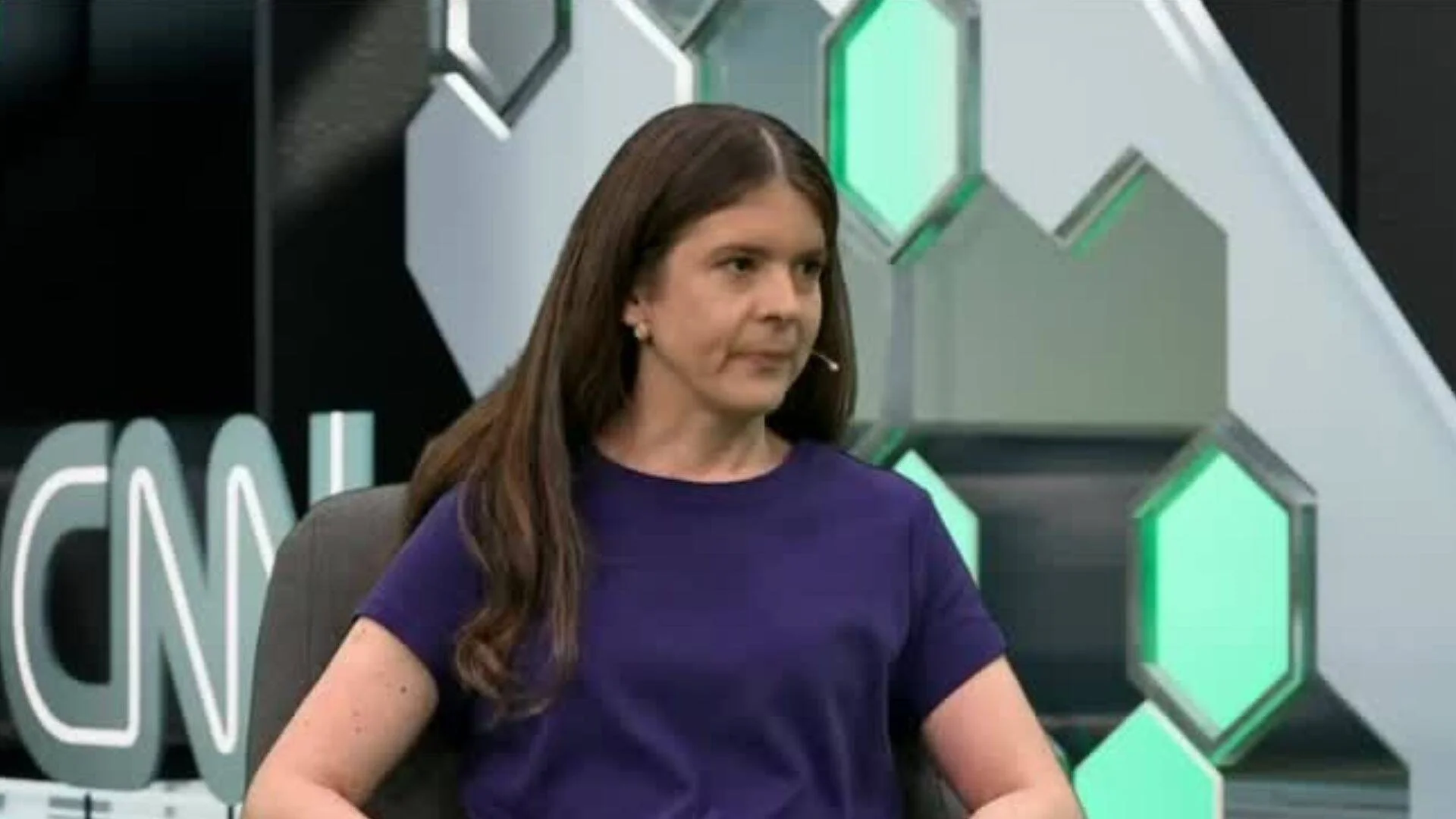 Mujer de cabello castaño con remera violeta sentada en el estudio de CNN con micrófono de solapa.