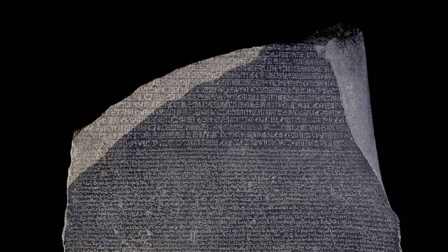 La Piedra de Rosetta, estela de granodiorita con inscripciones en jeroglíficos, demótico y griego antiguo, sobre fondo negro.