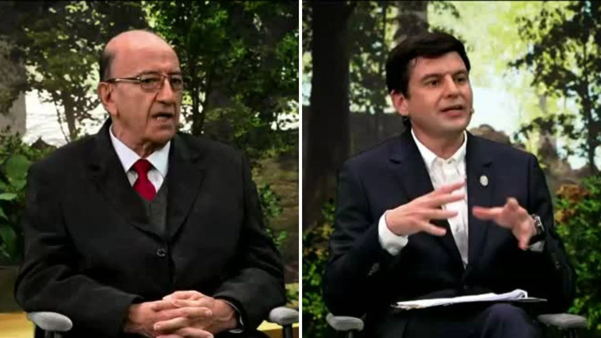 Dos hombres con traje oscuro sentados en un set al aire libre; el de la derecha gesticula mientras sostiene papeles.