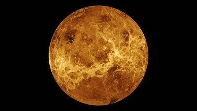 Vista global del planeta Venus mostrando su superficie de tonos anaranjados y marrones sobre fondo negro.