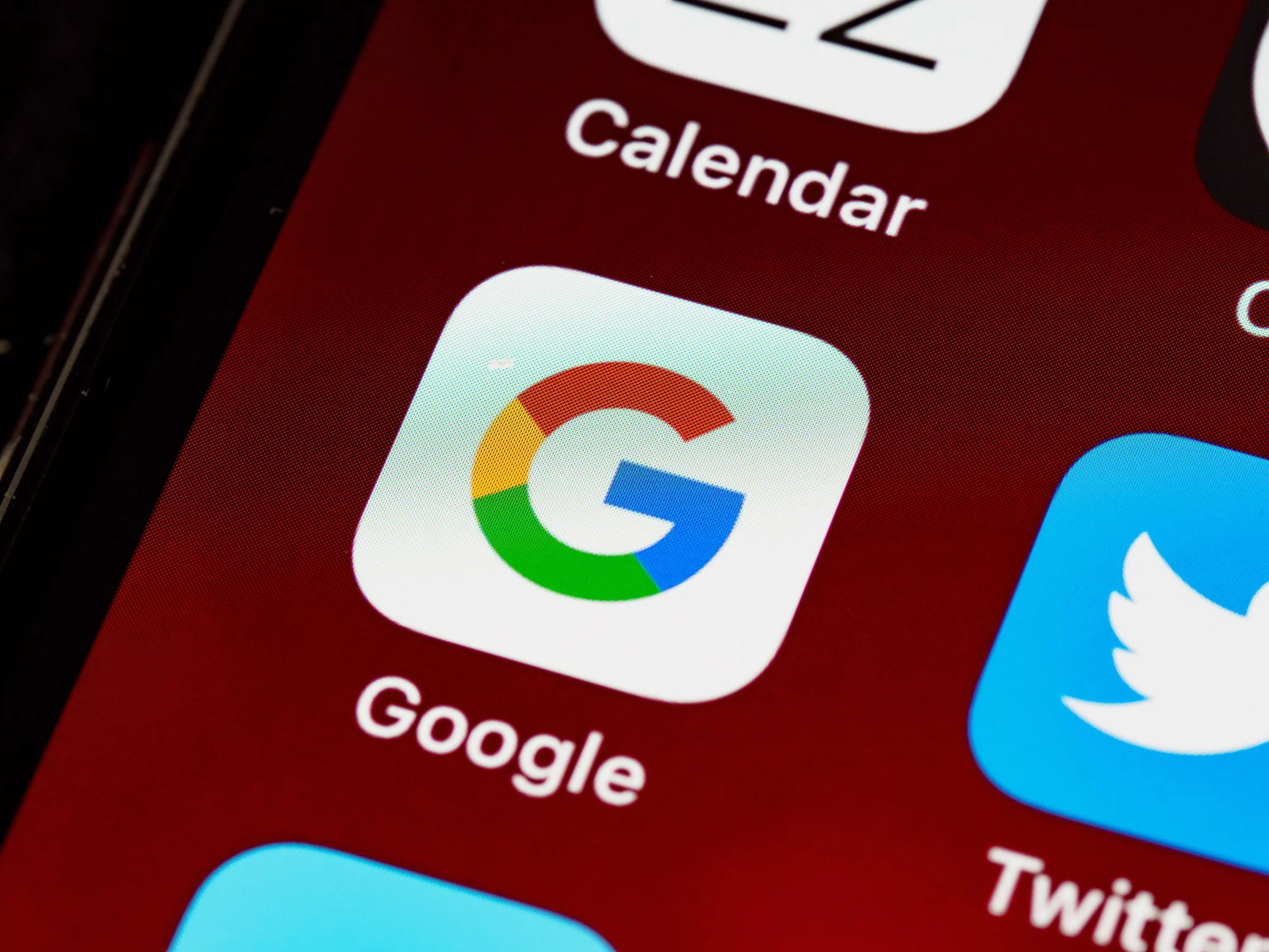 Pantalla de un smartphone con el ícono de la app de Google en primer plano, junto a las apps de Twitter y Calendar.