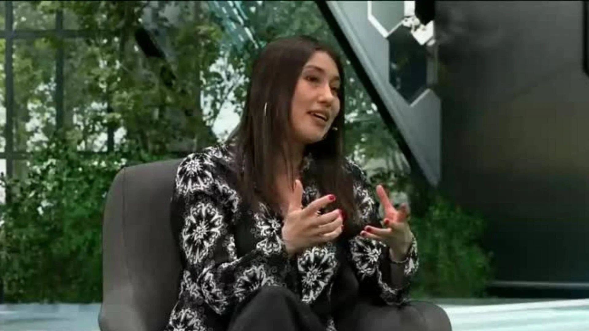 Mujer de cabello oscuro habla gesticulando con las manos durante una entrevista en un estudio de televisión.