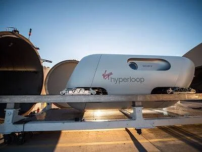 Cápsula futurista de Virgin Hyperloop posicionada frente a un túnel en una instalación de pruebas al aire libre.