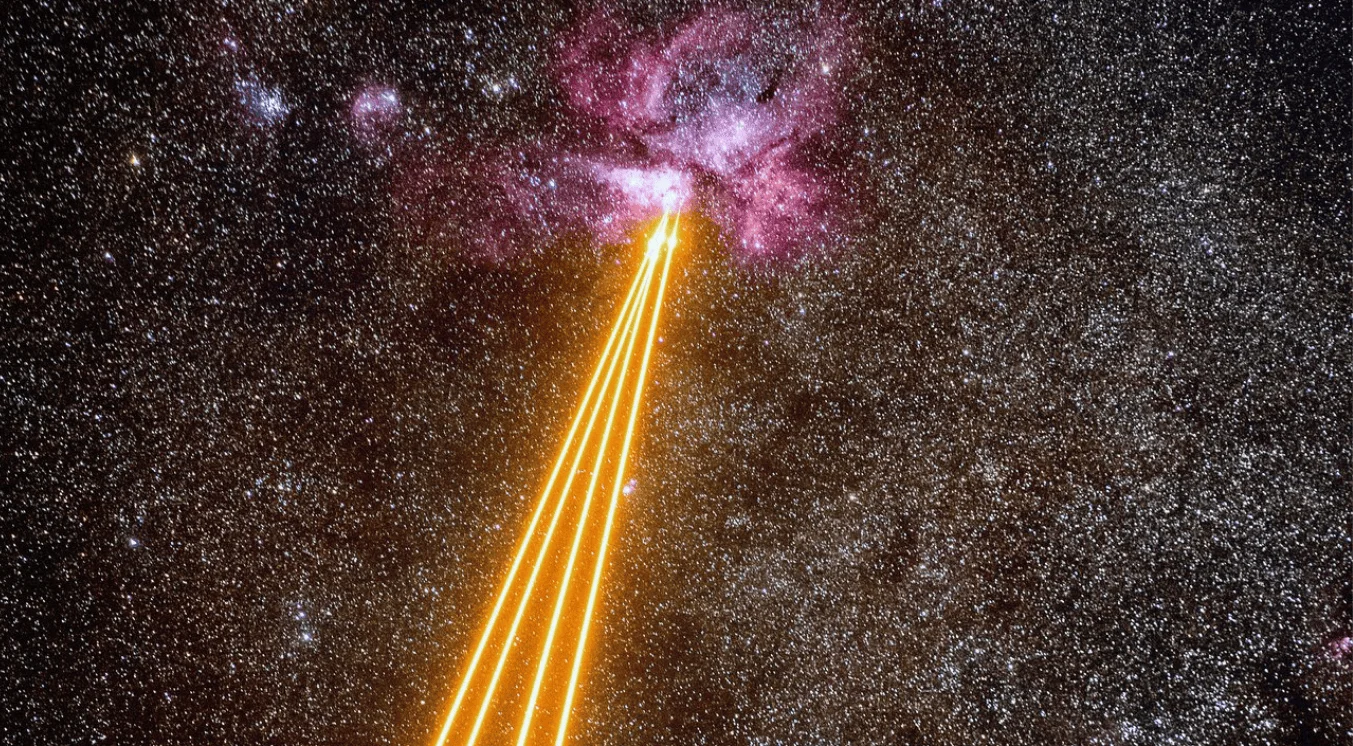 Ilustración de haces de luz naranja convergiendo hacia una nebulosa rosada en un cielo estrellado, representando emisiones de energía cósmica.
