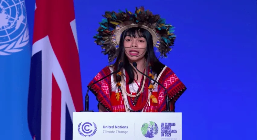 Joven con vestimenta y tocado indígena tradicional habla en el podio de la Conferencia de la ONU sobre Cambio Climático COP26.