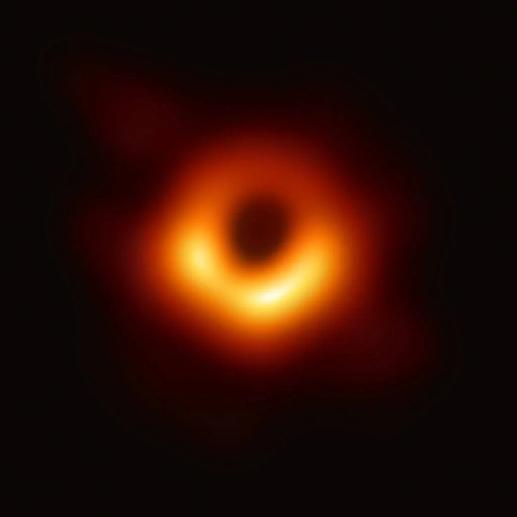 Anillo luminoso anaranjado que rodea la sombra oscura central de un agujero negro supermasivo, captado por el Telescopio de Horizonte de Sucesos.