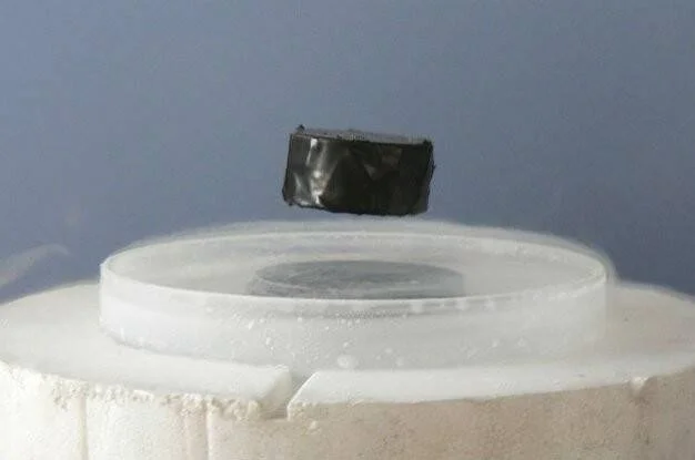 Un pequeño imán levita sobre un material superconductor enfriado con nitrógeno líquido, demostrando el efecto Meissner.